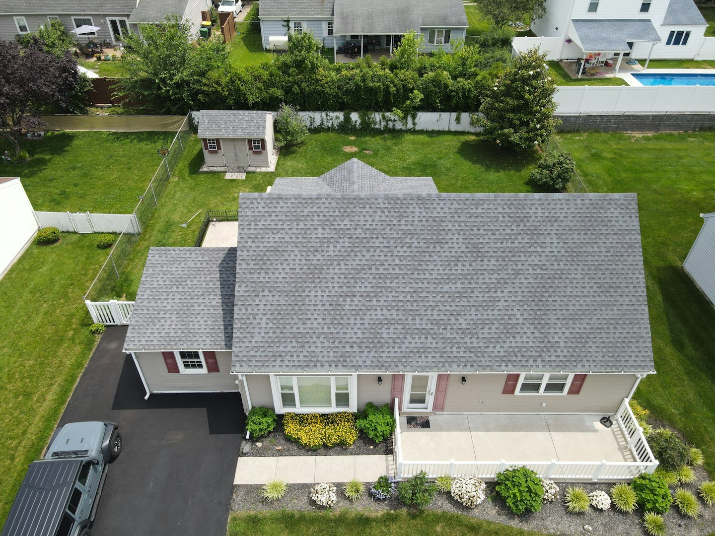 Suburban house with green lawn and parked SUV on a sunny day.